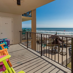 Relax on the vibrant balcony with colorful chairs, enjoying the beautiful view of the beach and sparkling water