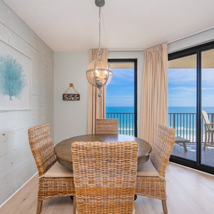 Rattan chairs invite you to gather around the dining table with shimmering gulf views beyond the sliding glass door