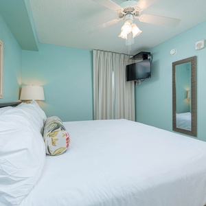 Relax in this inviting bedroom featuring a king bed, soft lighting, and a wall-mounted TV for your entertainment
