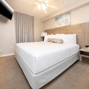 Rest comfortably in the inviting king suite featuring a plush bed, soft carpet, and a mounted TV for your entertainment