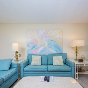 This living area features soft blue seating, a vibrant abstract painting, and a cozy atmosphere perfect for relaxation