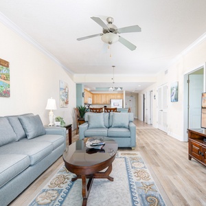 Bright and inviting living room featuring cozy blue sofas, a large TV, and beach-themed artwork for a relaxing atmosphere