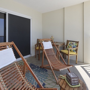 Relax on the balcony with wooden loungers and vibrant cushions, enjoying a stunning beachfront view