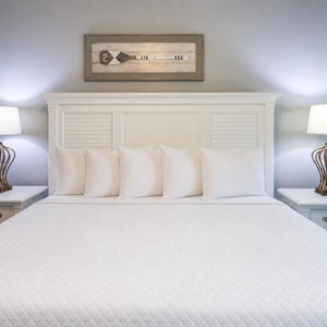 Sink into plush king bedding for a restful night, illuminated by soft bedside lamps for a cozy vibe in the master