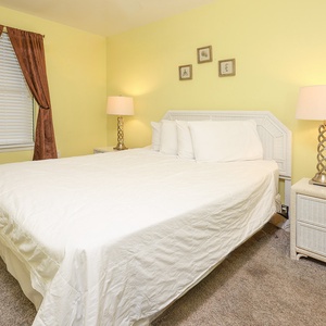 Bright yellow walls complement the cozy queen bed and warm lighting, creating a welcoming atmosphere in this guest bedroom