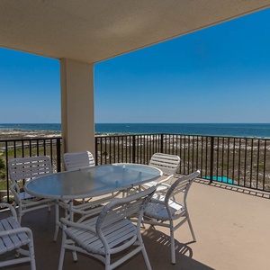 Relax on the extended balcony with a round table and white chairs, enjoying views of the beach and the inviting gulf waters