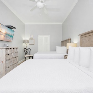 Rest comfortably in this inviting room featuring two queen beds, a wall-mounted TV, and stylish coastal decor
