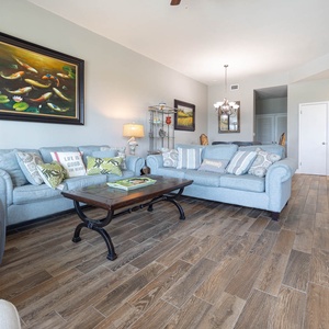 Light blue sofas with decorative pillows surround a wooden coffee table, creating a relaxed atmosphere in the living area