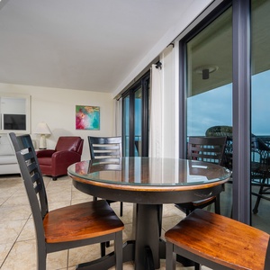 This inviting living area features a round dining table, a cozy red chair, and stunning views from the large glass doors