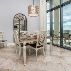 This dining area features a stylish table with elegant chairs, and large windows offering a stunning beachfront view