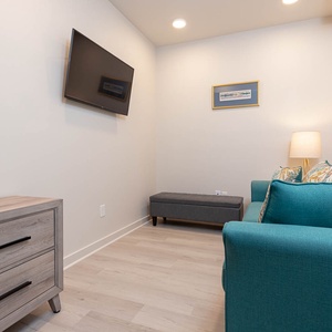 This cozy seating area features a turquoise sofa with decorative pillows, a mounted TV, and warm lighting for relaxation