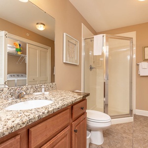 The extra bath features a stylish granite countertop, a spacious walk-in shower, and laundry area with a washer and dryer