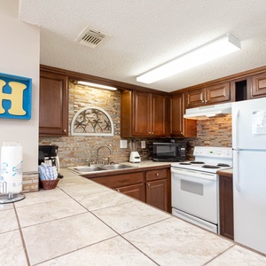 This kitchen features rich wooden cabinetry, a stylish backsplash, and essential appliances, perfect for meal preparation