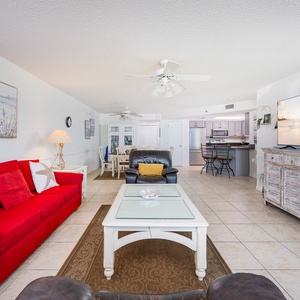 Bright red sofa with queen sleeper and cozy armchair create a welcoming living area, leading to the kitchen