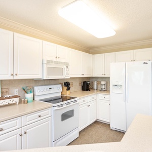 Prepare meals in the bright kitchen featuring sleek white cabinetry and a coffee corner with a Keurig and coffee maker