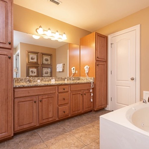 The master bath features elegant wood cabinetry, a granite countertop, and a relaxing jetted tub for a soothing retreat