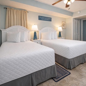 This bedroom features two comfortable beds, soft lighting, and beach-themed decor for a relaxing stay