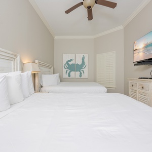 Relaxing guest bedroom featuring two cozy double beds, a TV, and charming coastal decor for a relaxing stay