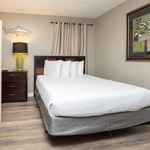 This guest room features a queen bed, a twin bunk bed, and colorful artwork, creating a welcoming atmosphere for families