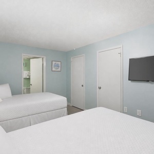 Rest in this inviting bedroom with two double beds, soft linens, and a TV during your stay