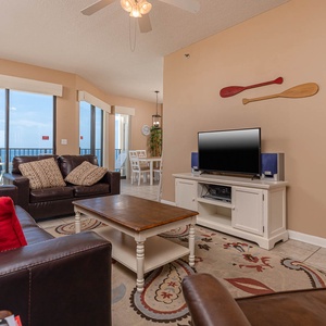 The inviting living area features a dark leather sofa with queen sleeper, a wooden coffee table, and a TV on a white console