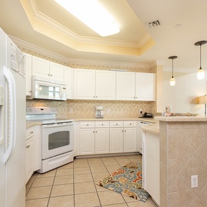 Prepare meals in this kitchen with sleek cabinetry, white appliances, and spacious countertops