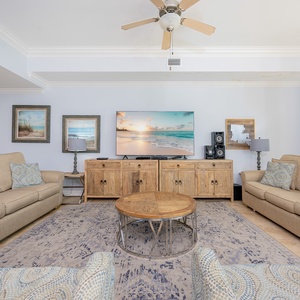 Relax in this inviting living room featuring comfortable sofas, a large TV, and coastal artwork enhancing the serene ambiance