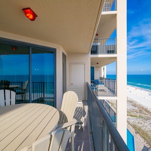 The balcony overlooks the coast with chairs and a table set for peaceful mornings or sunset views