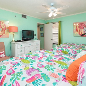 Guest bedroom featuring two colorful double beds, vibrant tropical decor, and a cozy seating area