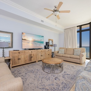 Living room featuring a large TV, cozy seating, and panoramic views of the tranquil waters beyond