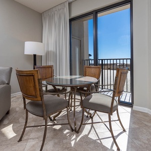 Dine at the glass-top table surrounded by stylish chairs, with natural light streaming in from the patio