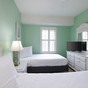 Bright turquoise walls complement two twin beds and a TV in this inviting guest bedroom, perfect for a relaxing getaway