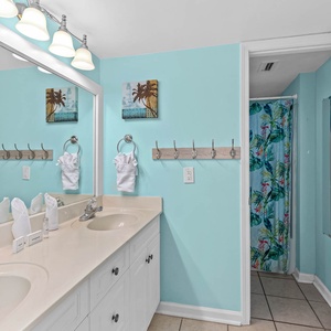 Guest bathroom with a dual sink vanity, tropical decor, and a colorful shower curtain for a refreshing vibe