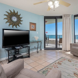 Living area features a large TV, sofa with queen sleeper, and sliding glass doors opening to a balcony with a gulf view