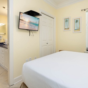 Cozy guest space a queen bed, wall-mounted TV, and shared bathroom space, creating a relaxed atmosphere