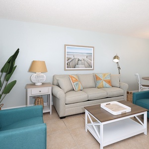Relax in the inviting living area featuring comfortable seating, beach decor, and a dining space nearby