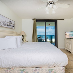 Master bedroom featuring a king bed, a TV, and a balcony with a stunning view of the beach and gulf waters