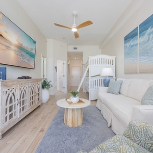 The spacious living room features stylish coastal decor, comfortable seating, and a large flat-screen TV perfect for relaxing movie nights