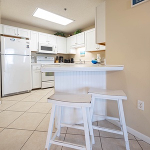 Bright white cabinetry and a breakfast bar with stools enhance this fully-equipped kitchen, perfect for meal prep