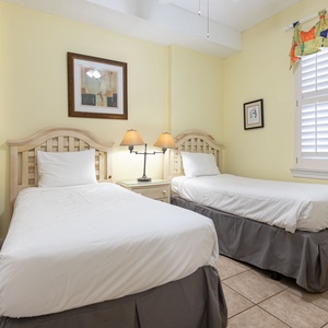This guest bedroom features two twin beds, soft yellow walls, and charming decor, creating a bright and cheerful retreat
