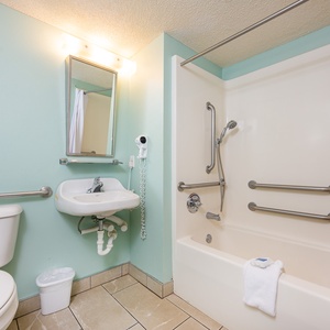 The accessible bathroom features bathroom and shower rails and a shower chair for safety and comfort