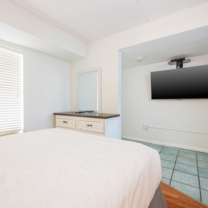 The master bedroom features a comfortable bed, a mounted TV, and a stylish dresser, perfect for a relaxing getaway