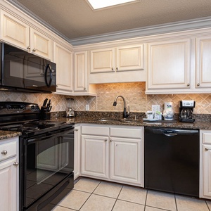 The kitchen features black appliances, light cabinetry, and granite countertops, creating an inviting cooking space