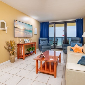 Cozy living area featuring a large TV, vibrant decor, queen sofa-sleeper, and a stunning balcony beach view