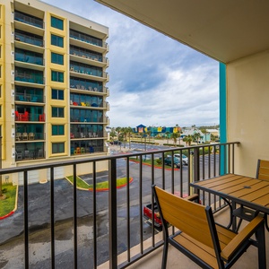 Enjoy a relaxing moment on the balcony with a view of colorful buildings and outdoor seating, perfect for unwinding