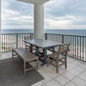 This sixth-floor balcony features a dining table and chairs, perfect for enjoying meals with a beachfront view