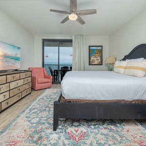 Relax in this spacious master bedroom featuring a large king bed, vibrant decor, and beachfront balcony access