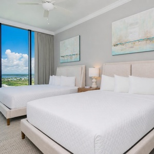 Relax in this guest bedroom featuring two queen beds and expansive windows showcasing scenic views