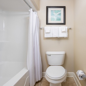 Refresh in the guest bathroom featuring a tub-shower, soft towels, and coastal decor