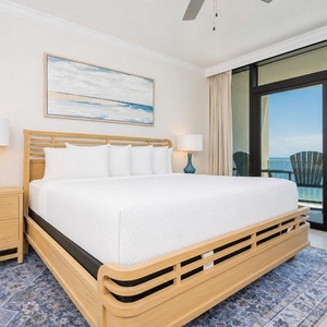 Relax in this tranquil master bedroom featuring a king bed, stylish decor, and a view of the beachfront balcony